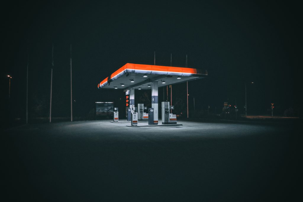An isolated and illuminated gas station at night, highlighting urban solitude under a dark sky.